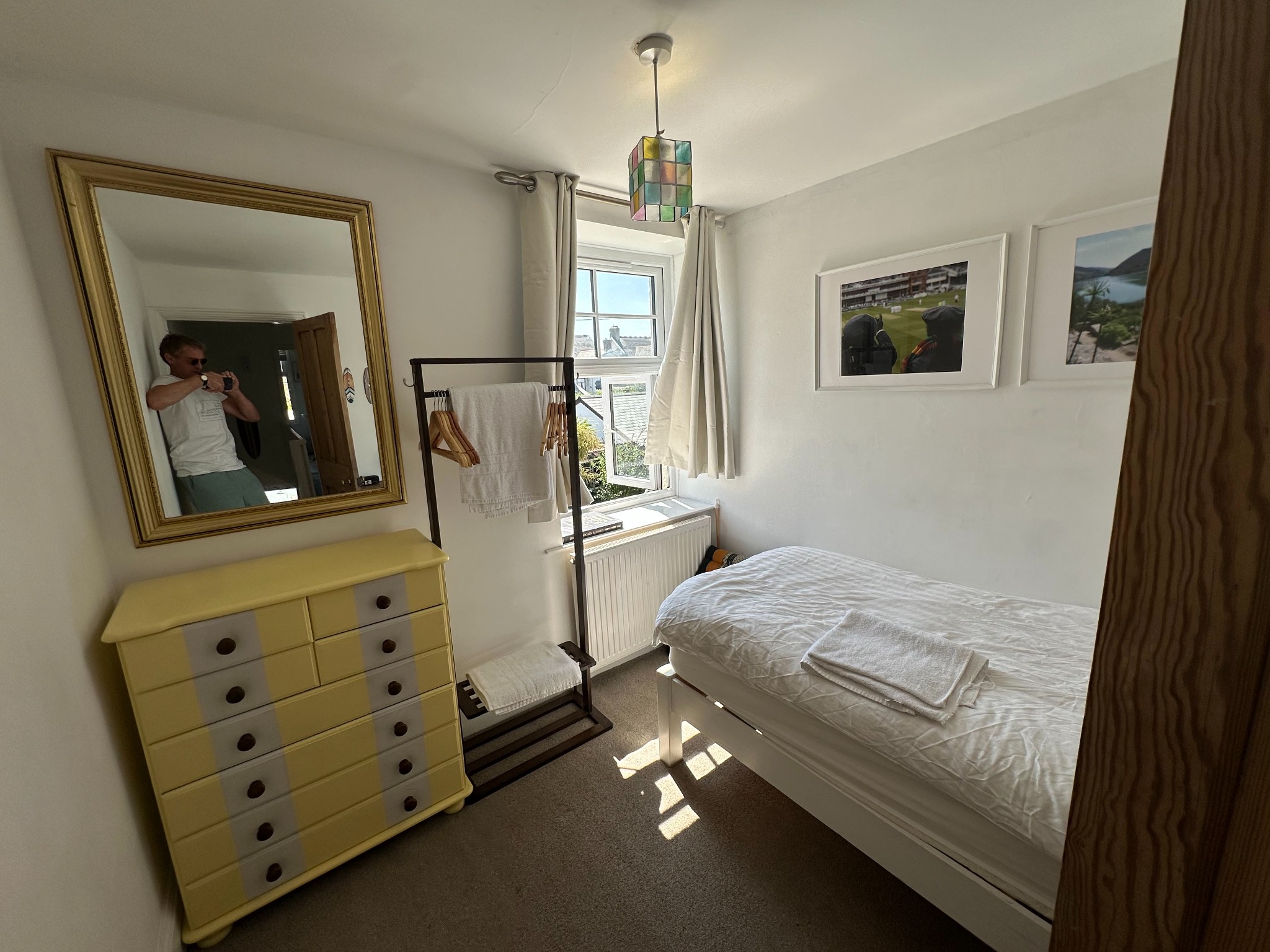 Second view of the single bedroom with a window and storage