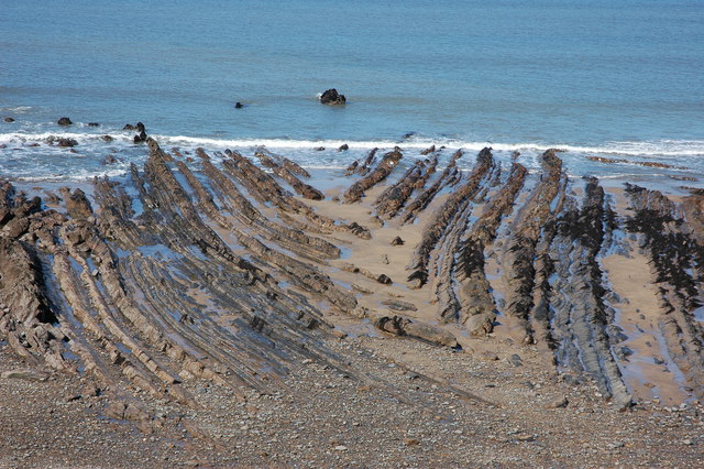 Dramatic folded rock formations and clear blue water at Crooklets Beach at low tide