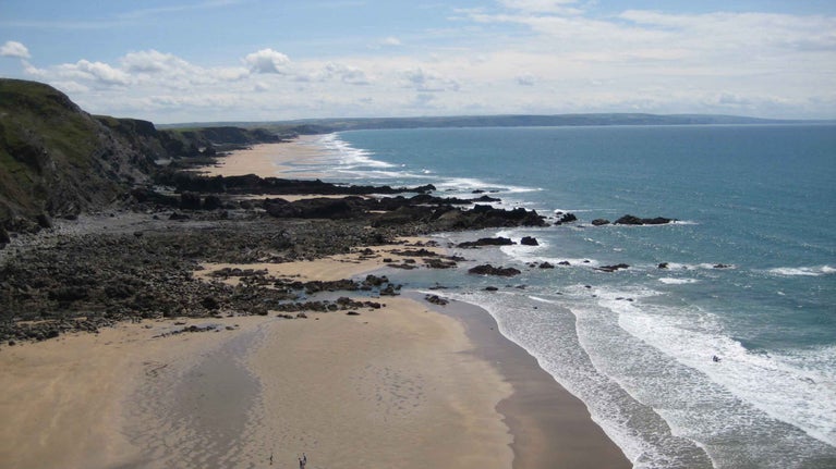 Duckpool Beach beneath steep grassy cliffs on the North Cornwall coast