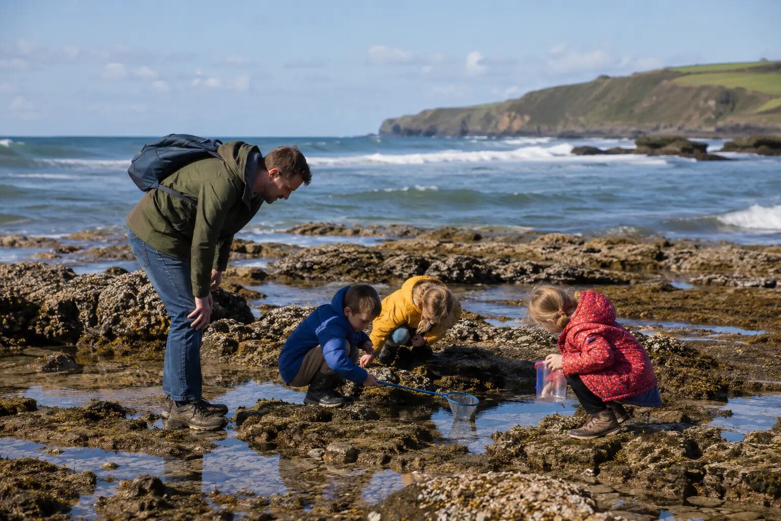 Children exploring rock pools with an adult near Bude in North Cornwall