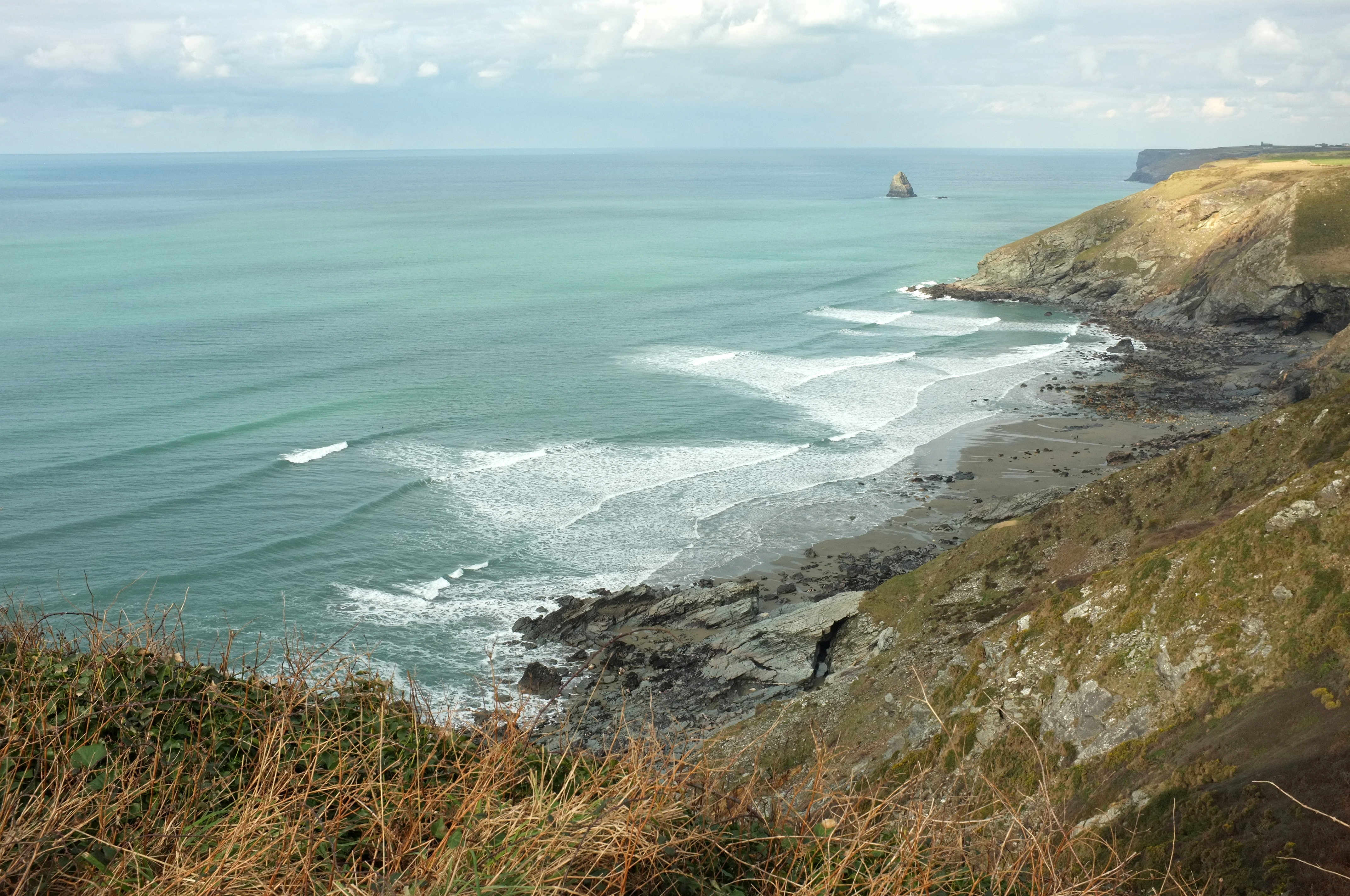 Tregardock's remote Atlantic bay framed by steep dark cliffs and clean swell lines